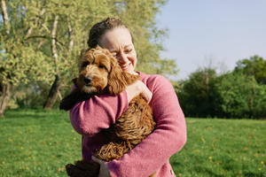 Woman cuddling her dog in a field