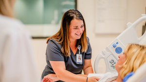 Medical assistant tending to elderly female patient in a hospital bed
