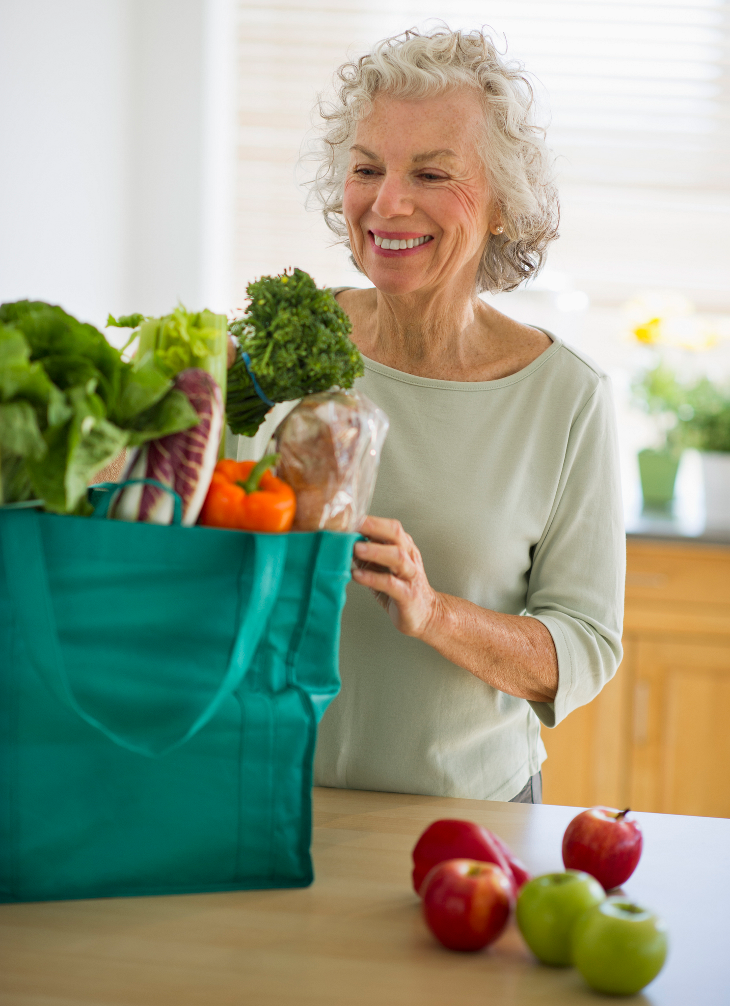 Senior woman with grocery bag in kitchen