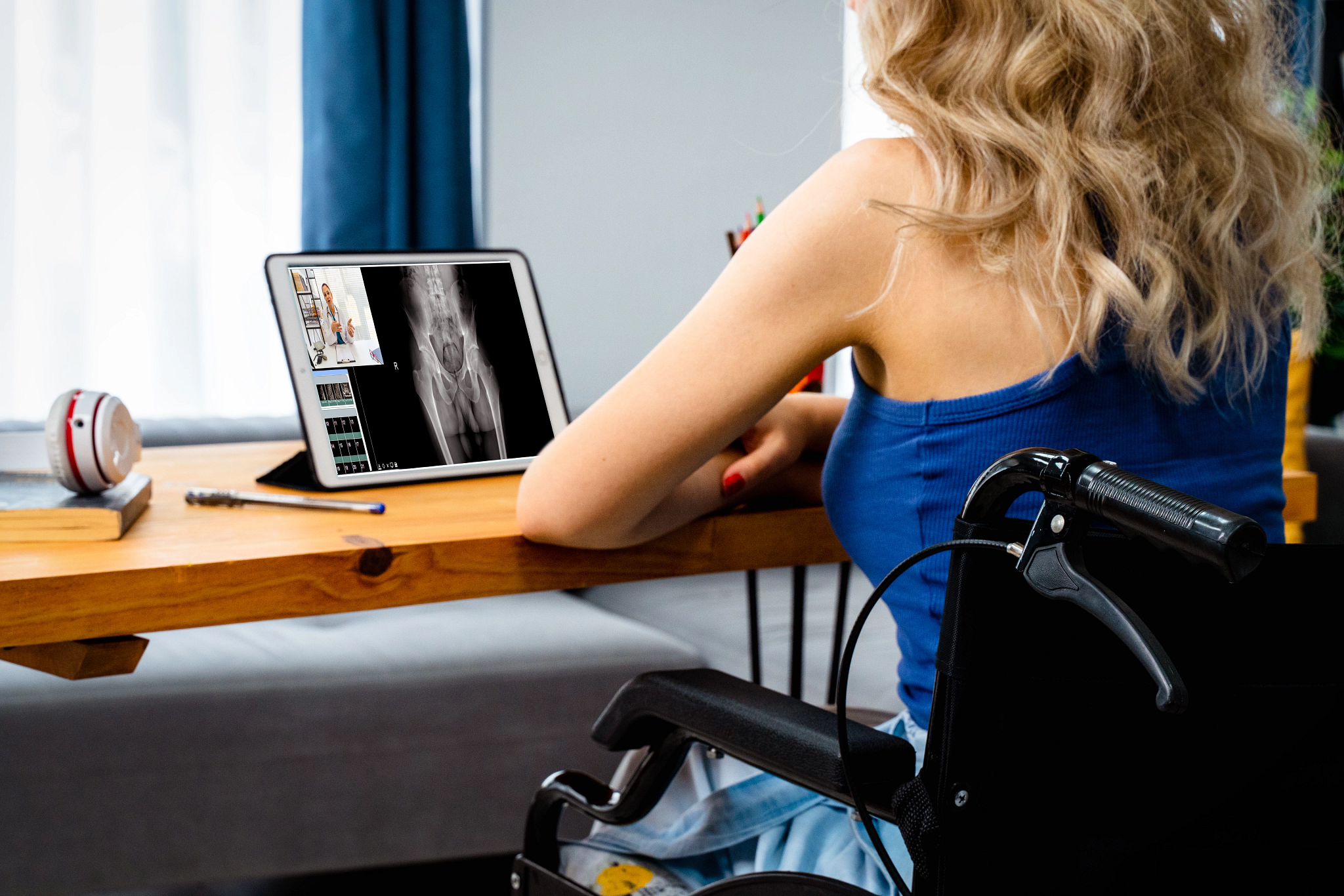 A female patient in a wheelchair meets with her doctor remotely via a video call.