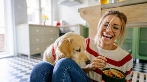 Young woman and her dog in a kitchen at the morning