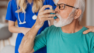 Senior man using asthma inhaler with provider.