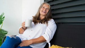 Mature woman enjoying a cup of coffee on her balcony.