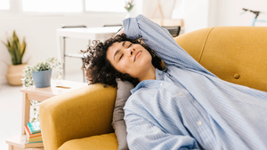 Smiling young woman with eyes closed resting on sofa at home