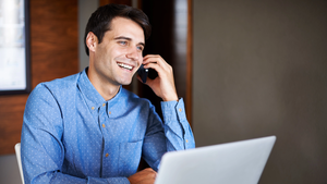 Smiling man using cell phone at desk in office