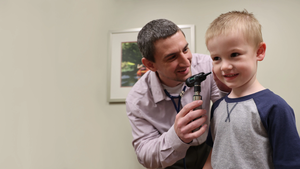 Dr. Tyler Manley performing wellness exam with young boy