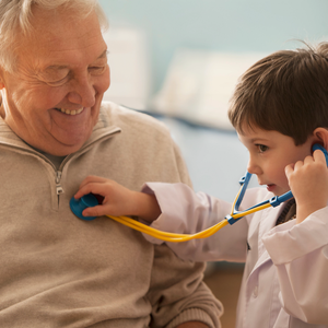 Caucasian boy listening to grandfather's heartbeat with stethoscope