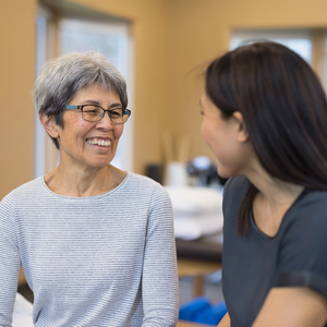 A physical therapist talks with her elderly patient in a clinic.