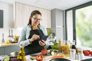 Woman cooking and using mobile phone in kitchen
