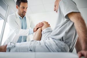 Doctor examining knee on senior patient