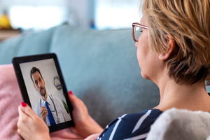 Woman using tablet for e-visit with her doctor while at home