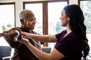 Nurse helping senior woman with physical therapy