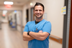 male nurse standing in hallway with arms crossed